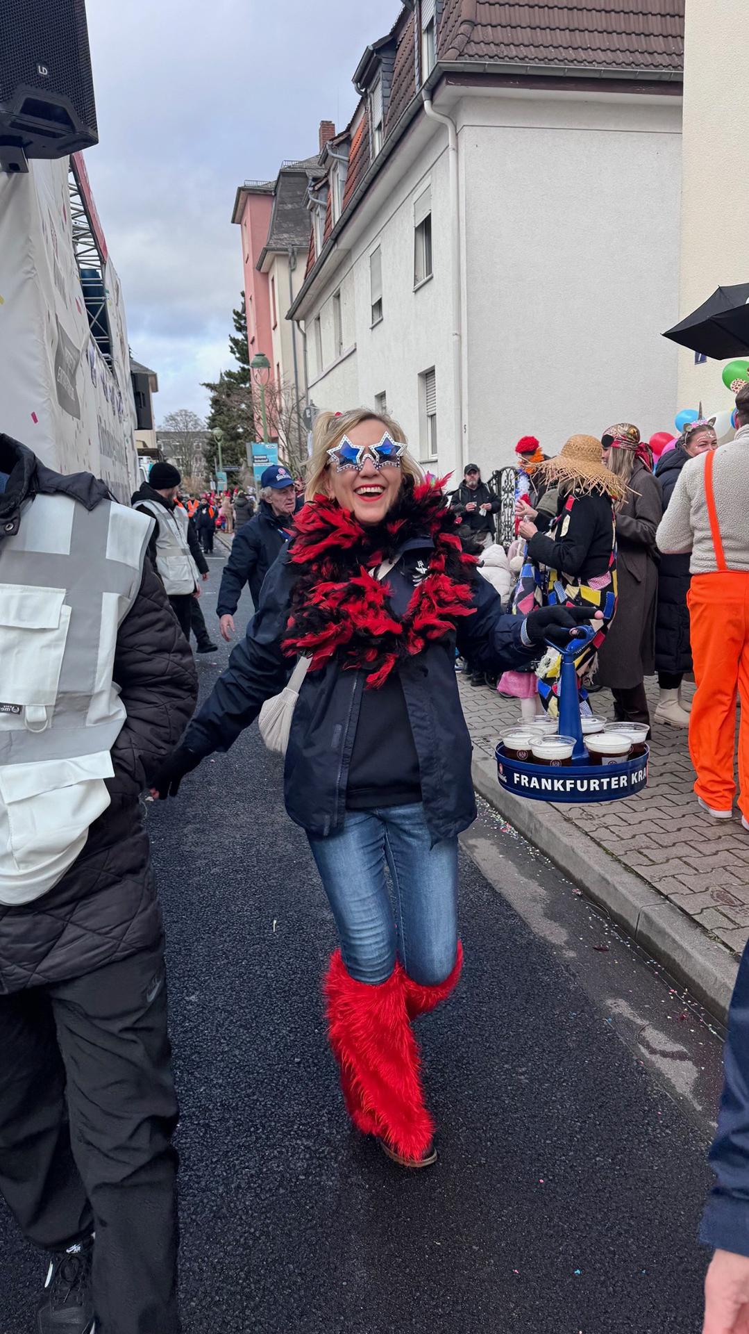 Eine verkleidete Frau hält einen Bierkranz mit mehreren Bierbechern in der Hand.