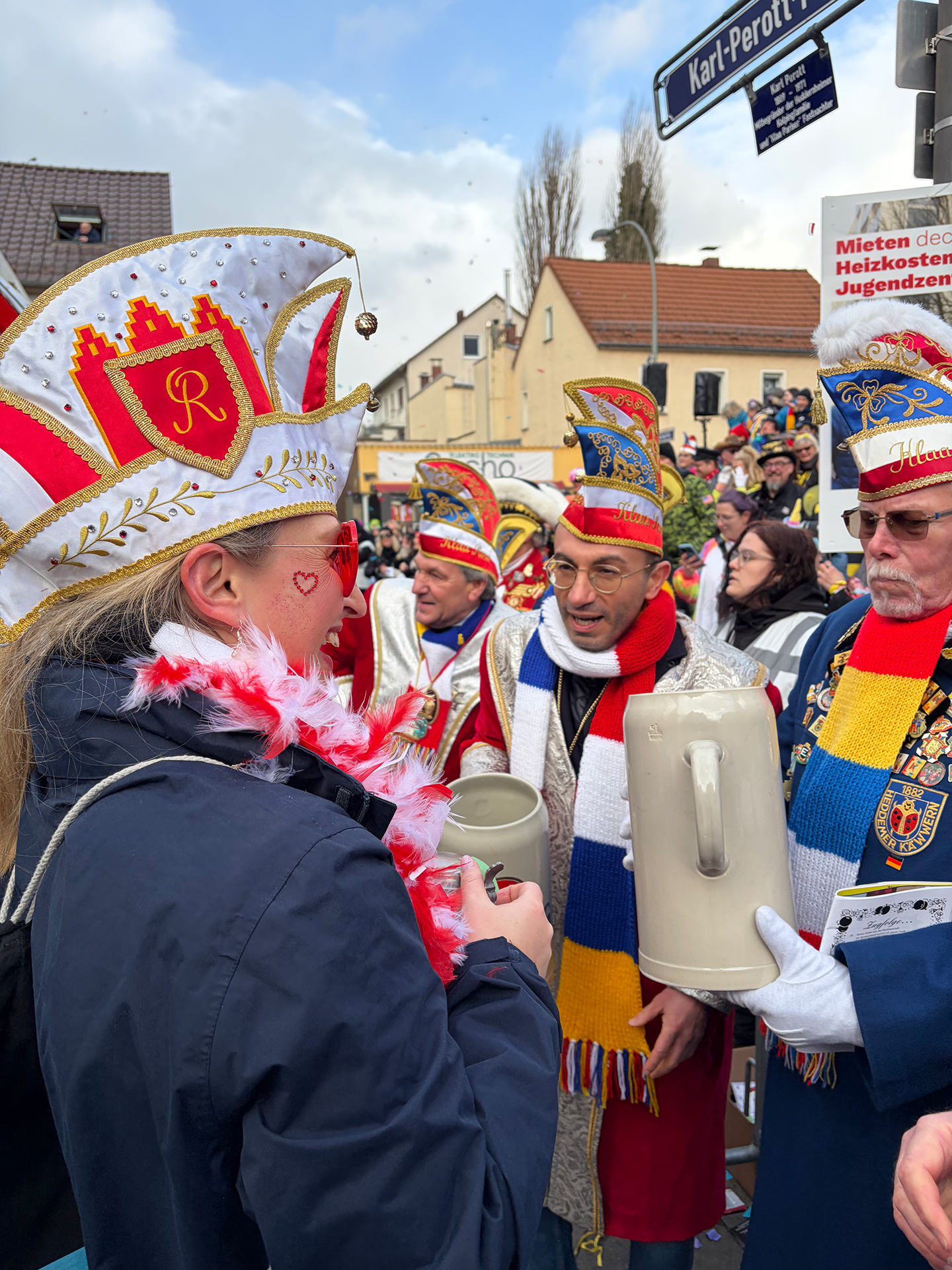 Mehrere Personen in Fastnachtskleidung halten beim Feiern große Bierkrüge in den Händen.