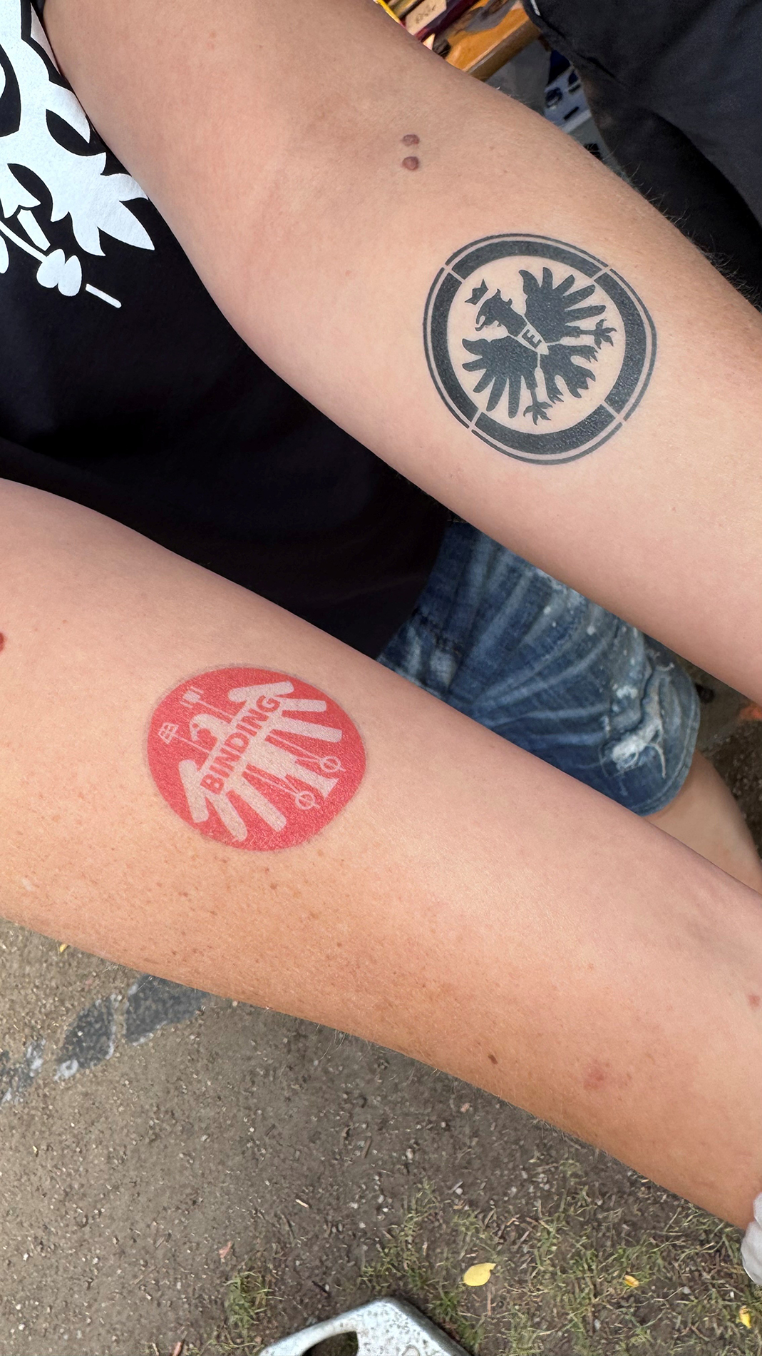 Zwei Unterarme mit jeweils einem Tattoo von Binding und dem Eintrachtadler.