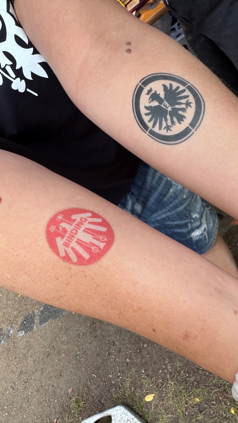 Zwei Unterarme mit jeweils einem Tattoo von Binding und dem Eintrachtadler.