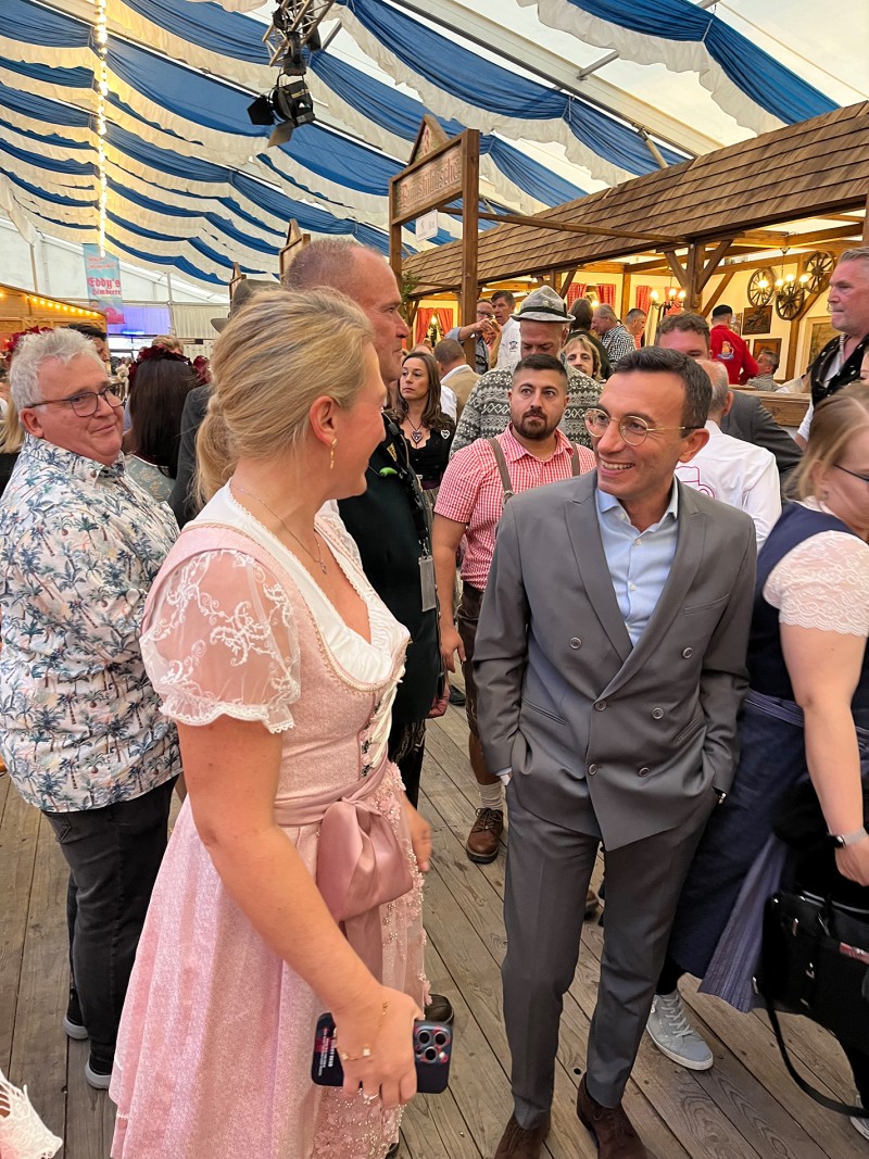 Mehrere Personen unterhalten sich in einem Bierzelt.