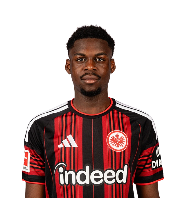 Mann mit kurzem schwarzem Haar und Kinnbart blickt frontal in die Kamera und trägt ein Trikot der Eintracht Frankfurt.