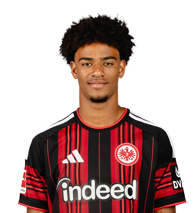 Mit voluminösen schwarzen Locken und kurzem Kinnbart lächelt der Mann im schwarz-roten Eintracht Frankfurt Fußball-Trikot.