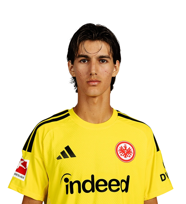 Mit mittellangen dunklen Haaren und Strähnen an der Stirn trägt ein Mann ein gelbes Eintracht Frankfurt Torwarttrikot.
