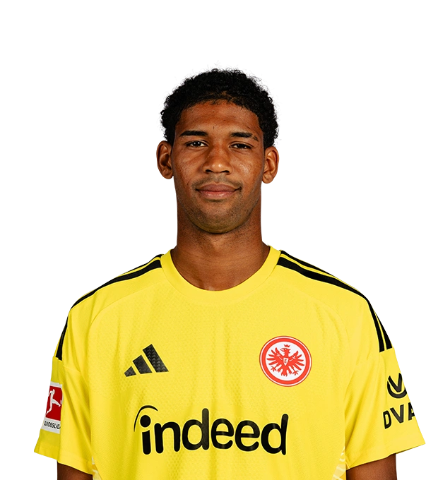 Im gelben Torwarttrikot blickt der Spieler mit kurzen schwarzen Locken und leichtem Lächeln frontal nach vorn.