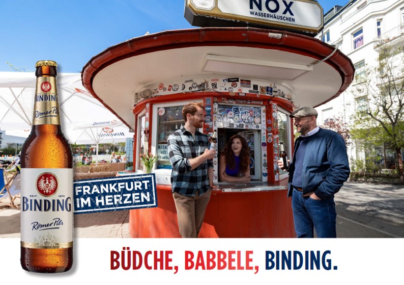 Zwei Personen trinken Binding Bier vor einem Wasserhäuschen in Frankfurt.
