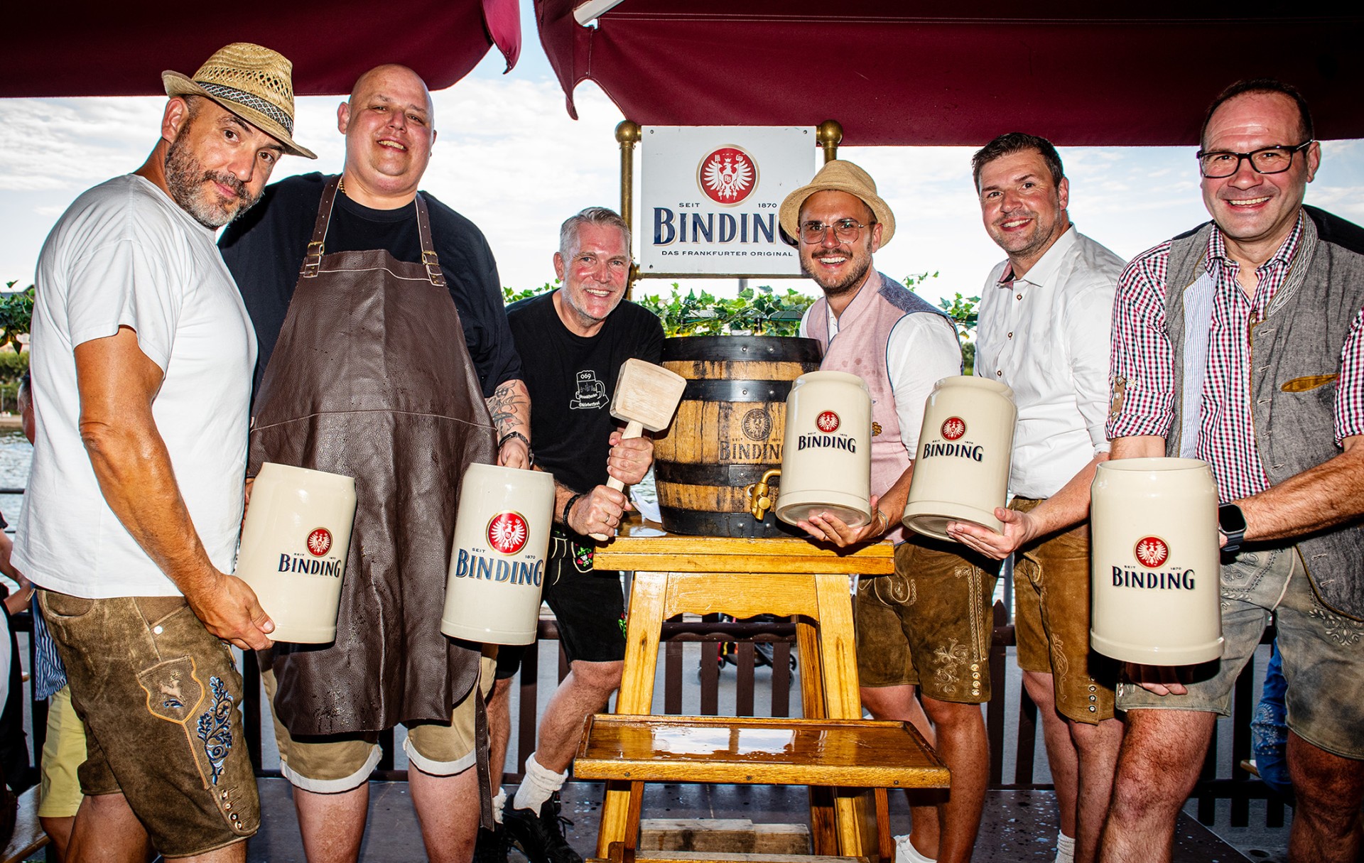 Sechs Personen stehen neben einem Binding Festbier Bierfass an und lächeln in die Kamera.